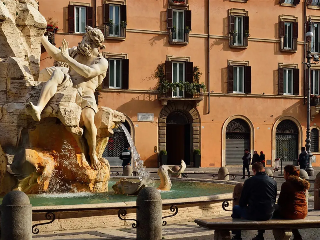 A Bernini fountain in front of the ochre facade on Piazza Navona.
