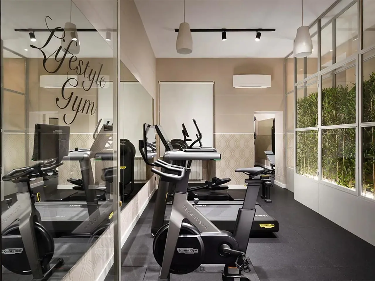 Small hotel gym with exercise bikes and a glass wall.