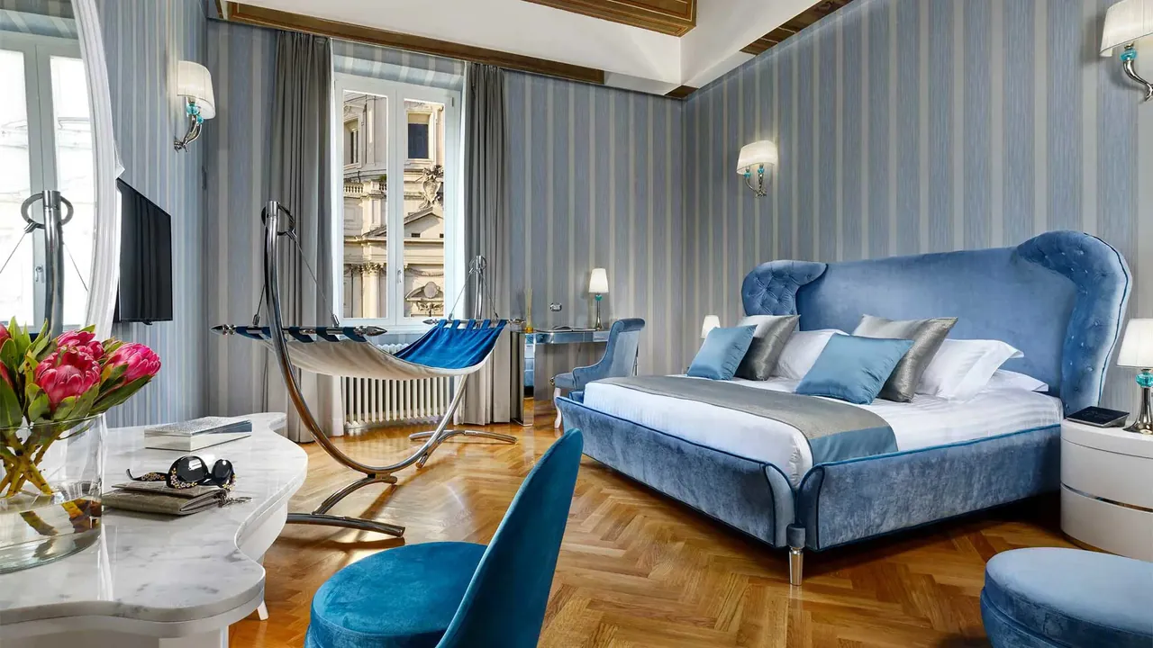 Suite with a blue upholstered bed, a hammock and striped walls.