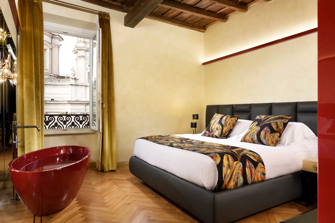 Suite with a red freestanding bathtub next to the bed.