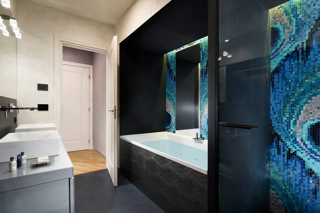 Bathroom with a bathtub and a glass mosaic wall.