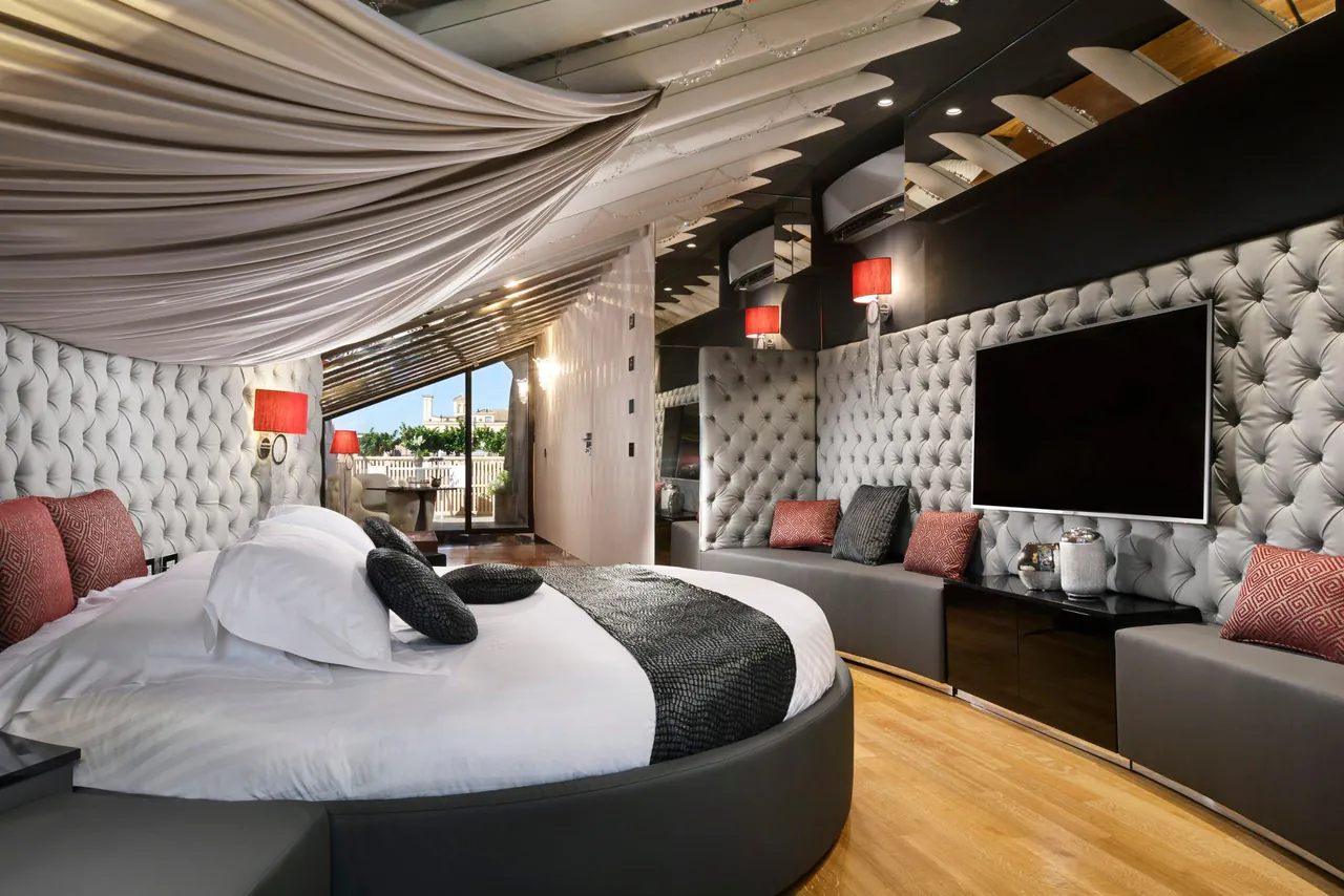 Suite with a round bed under a draped canopy and padded walls.