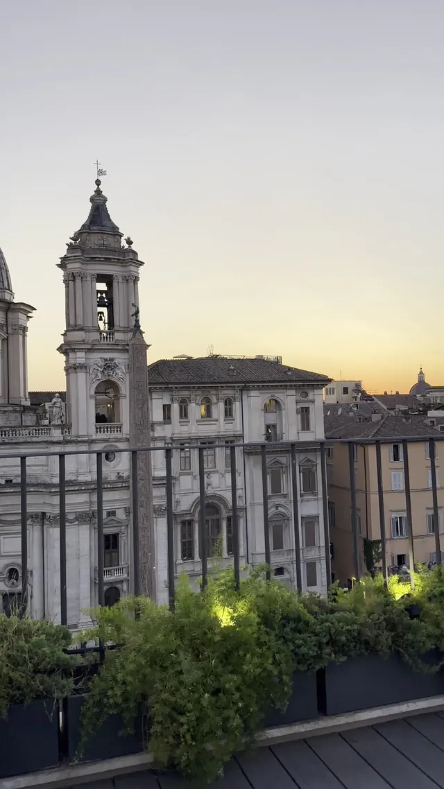 View of the piazza rooftops and a bell tower at dusk.