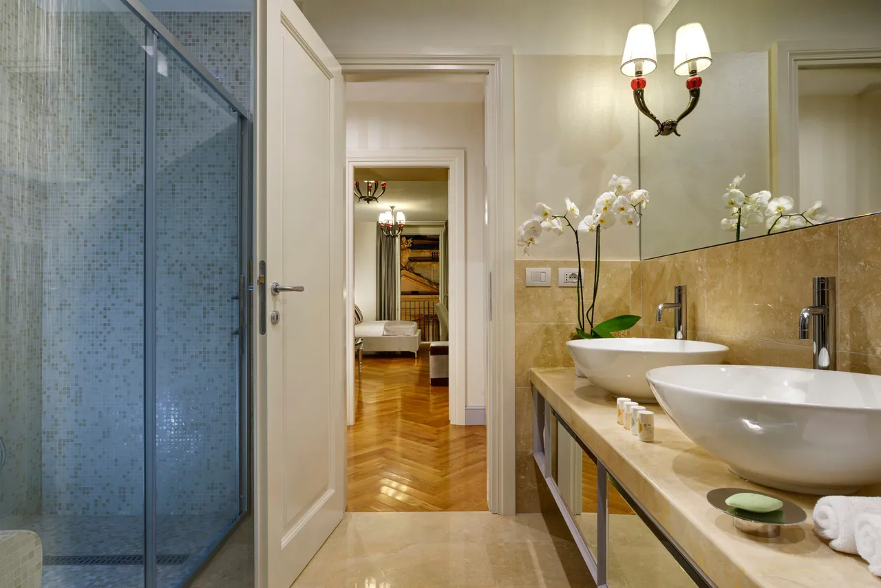 Marble bathroom with twin vessel basins and fresh orchids.