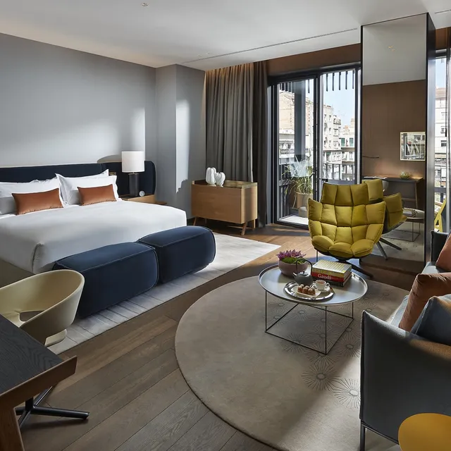Room at Mandarin Oriental, Barcelona, with a navy bench, yellow lounge chair and balcony doors to the street