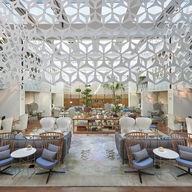 Atrium restaurant at Mandarin Oriental, Barcelona, under a white lattice canopy with blue armchairs