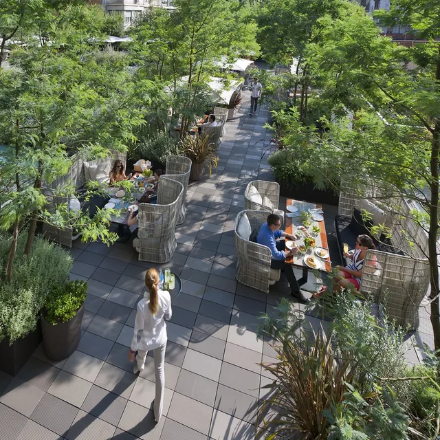 Garden terrace at Mandarin Oriental, Barcelona, with guests dining in wicker booth chairs among trees