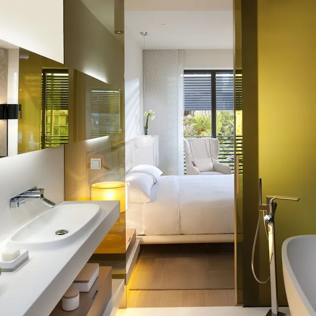 Room at Mandarin Oriental, Barcelona, seen from the bathroom, with a white bed, armchair and garden view