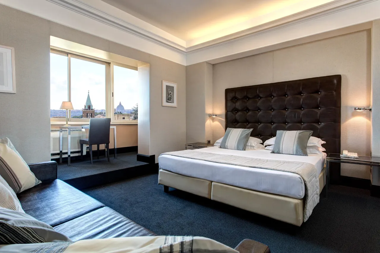A modern double room with a padded headboard and city views.