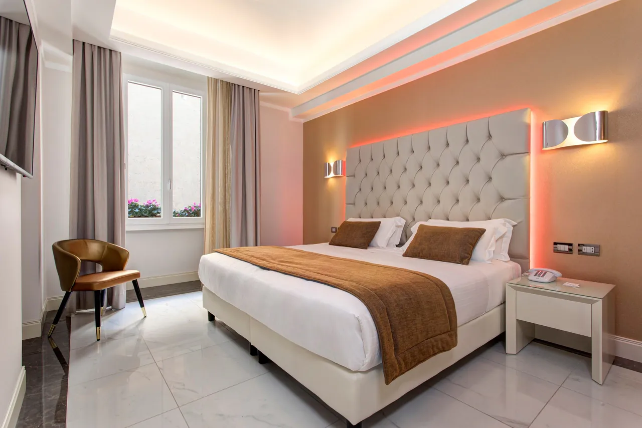 A bright double room with soft lighting and a leather armchair.