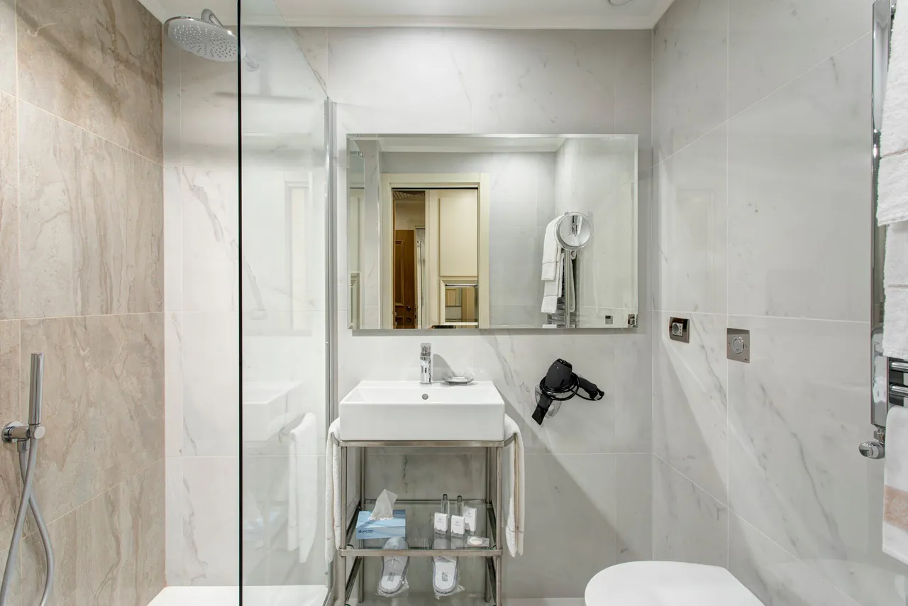 A white marble bathroom with a walk-in shower.