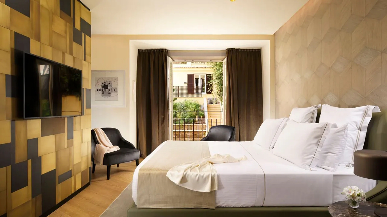 A Deluxe Suite bedroom with a white bed and a window onto the street.