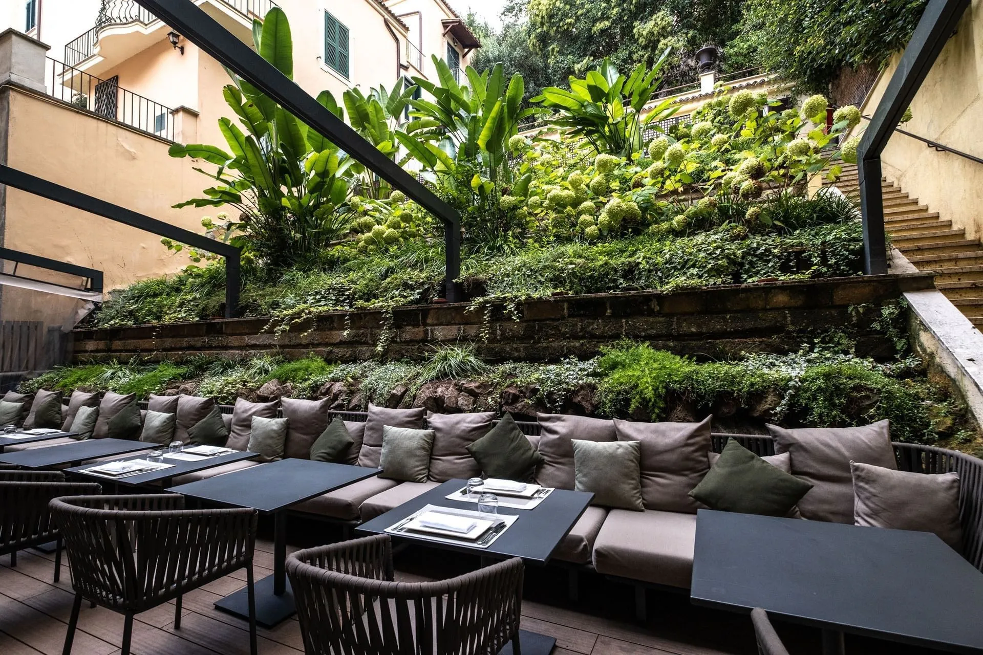 Sofas and tables in the EMME garden restaurant against a terraced green slope.