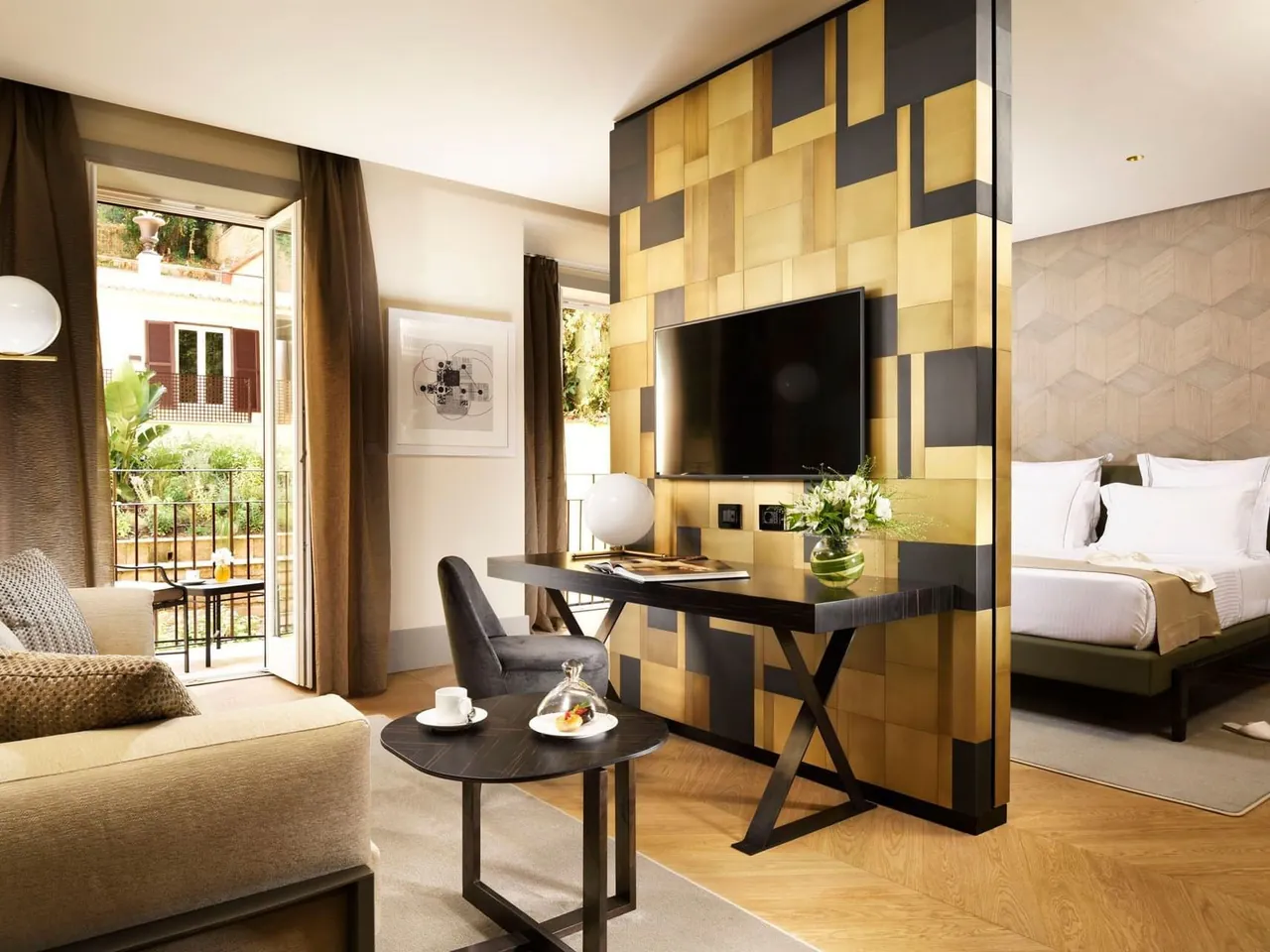 A Deluxe Suite with a gold panelled wall, a desk and the bedroom beyond.