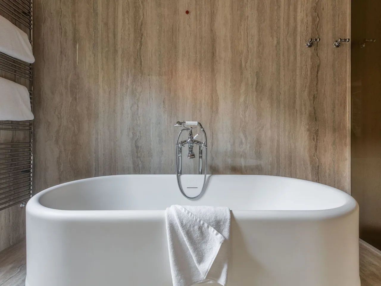 A freestanding bathtub in the stone lined bathroom of a Garden Suite.