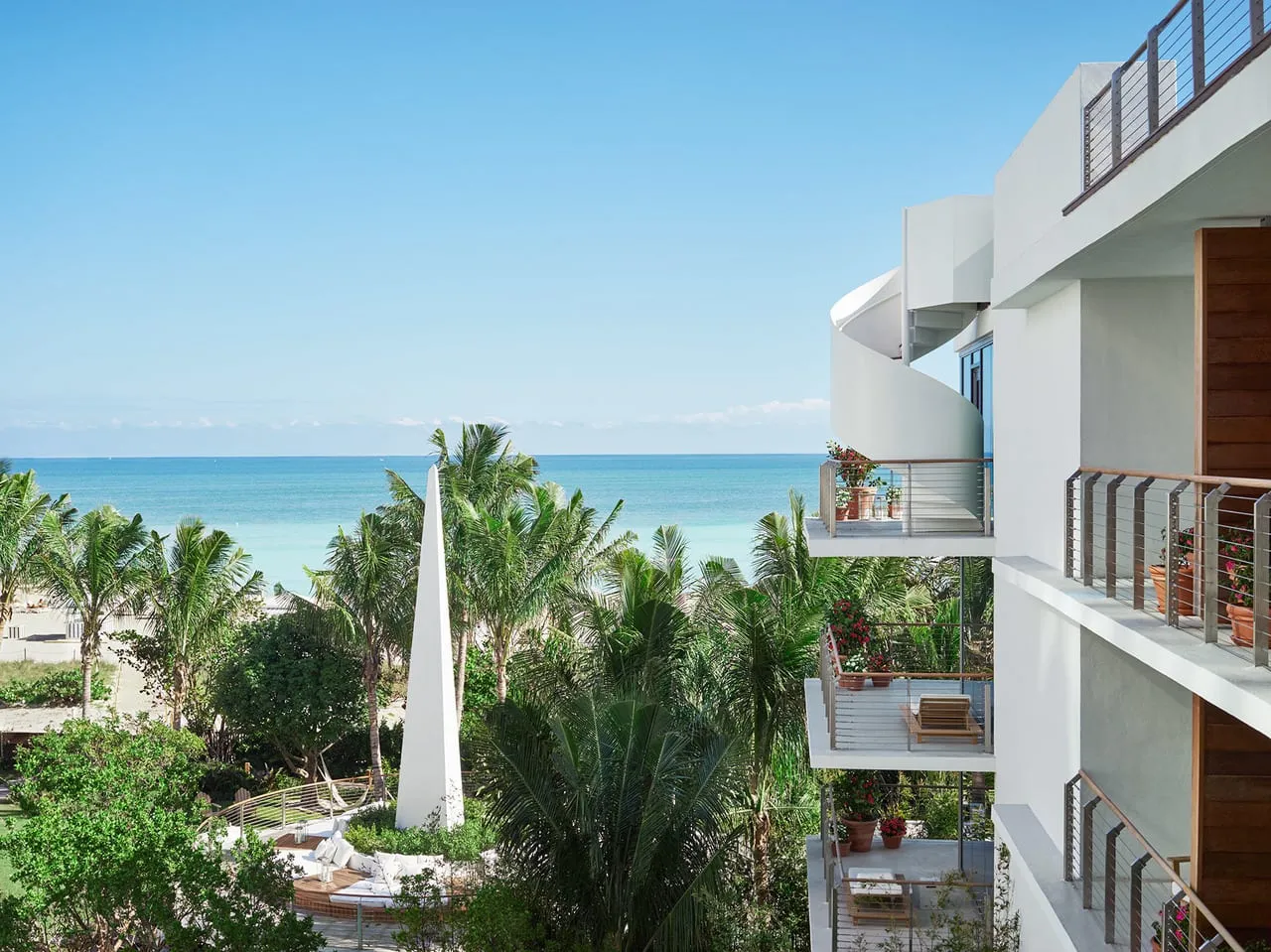 View from The Miami Beach Edition over palm gardens to the ocean, beside white curved balconies