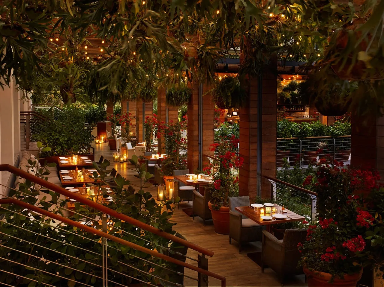 Candlelit garden restaurant terrace at The Miami Beach Edition with hanging plants and red flowers