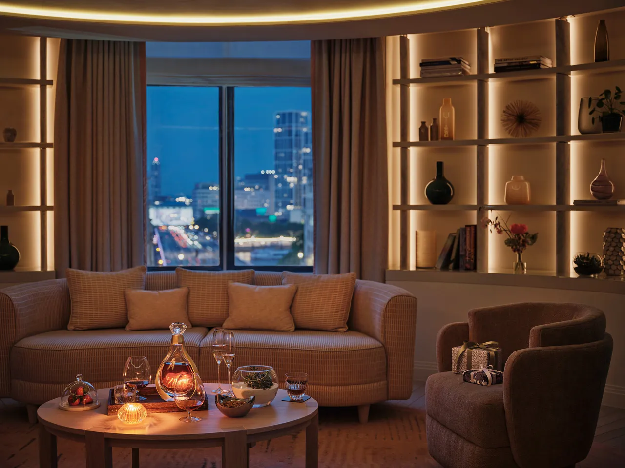 A suite lounge at night with city lights beyond the window.
