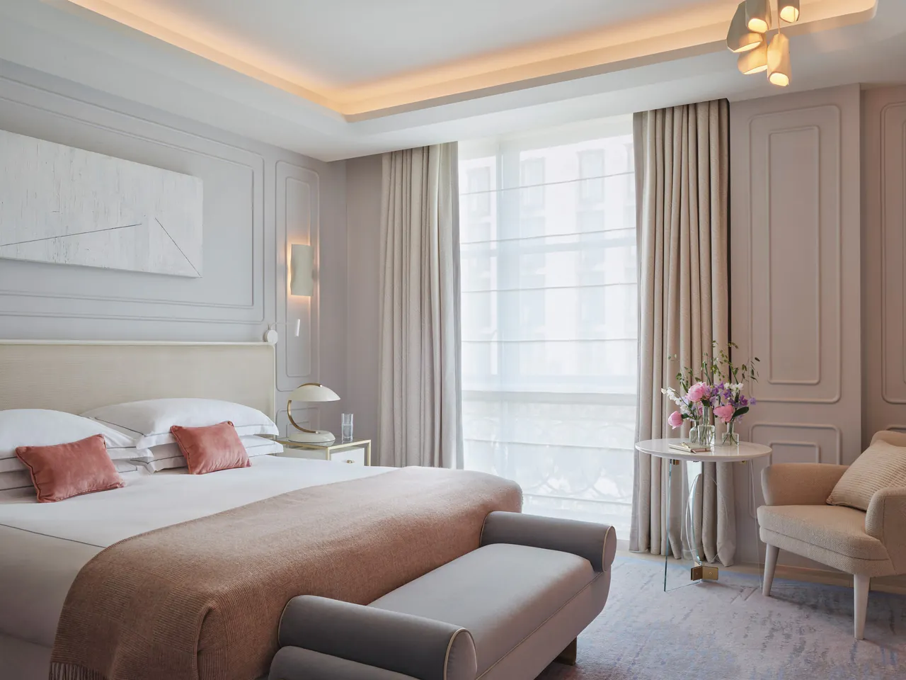 A superior room with a double bed, soft lighting and pale curtains.