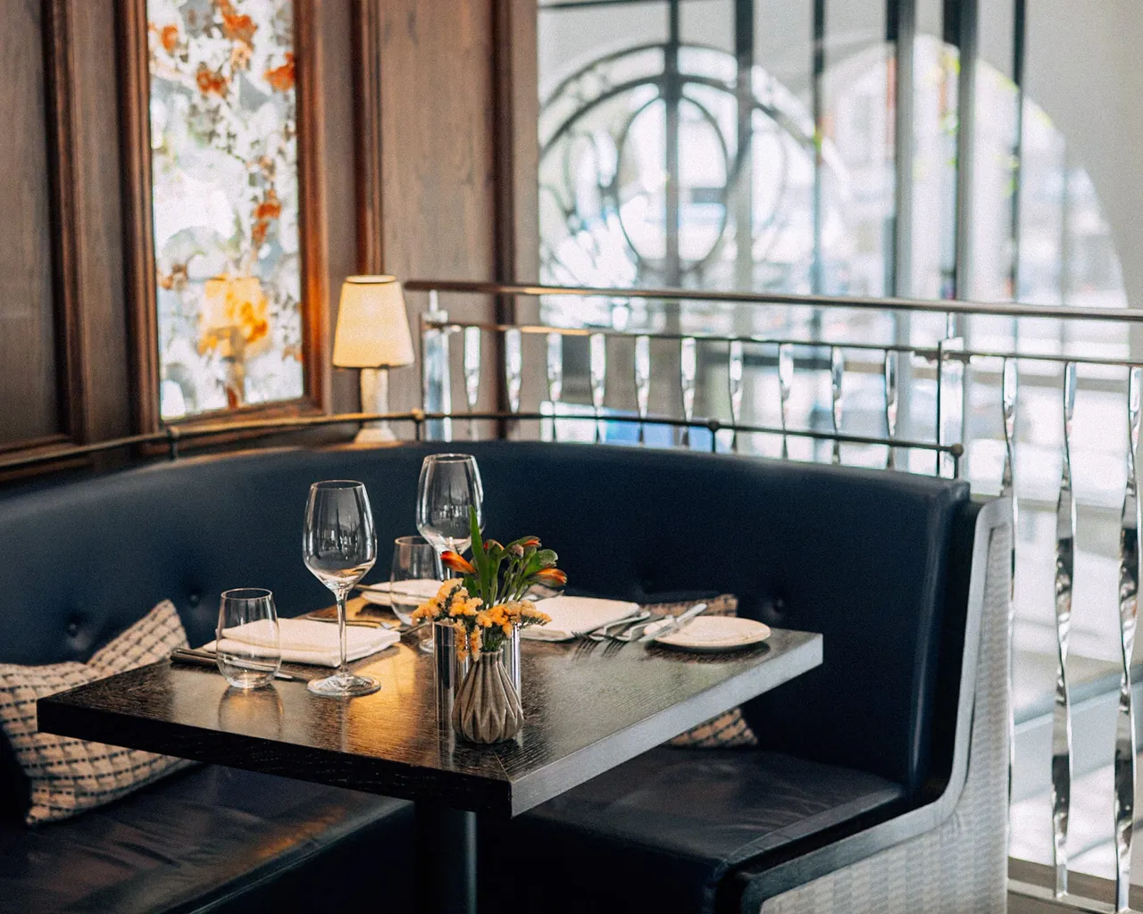 A dining booth at Indigo restaurant beside large arched windows.