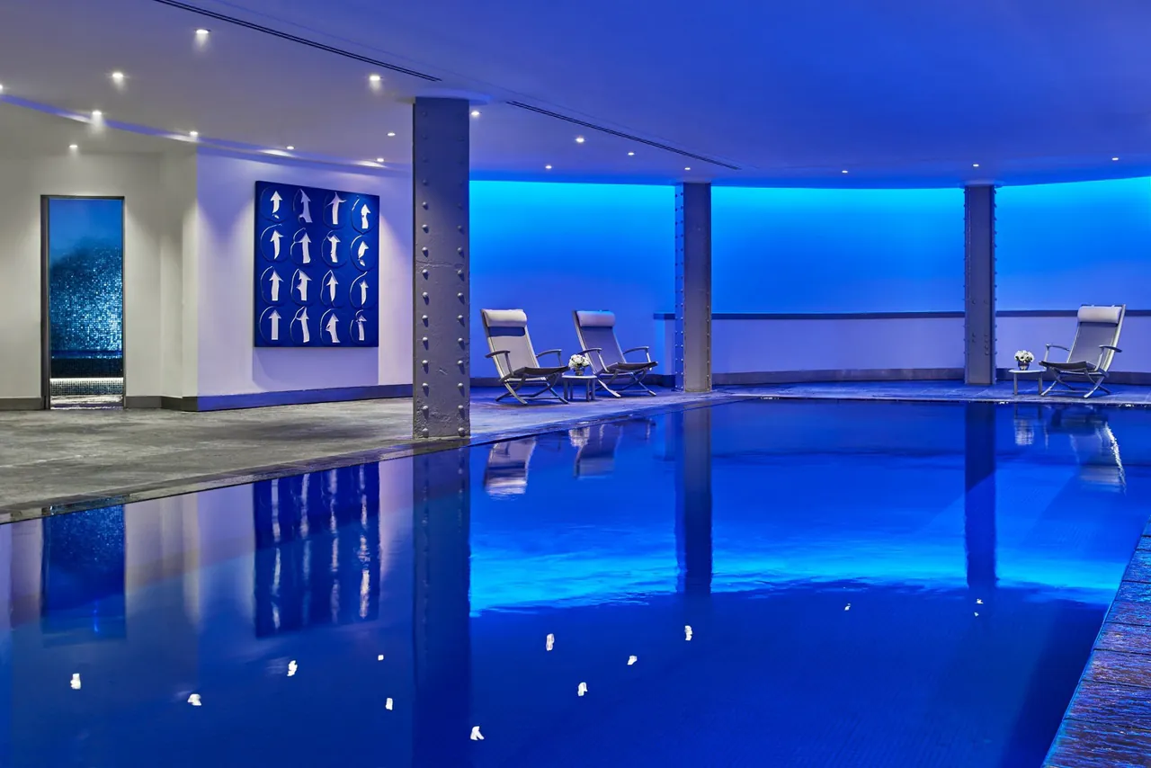 The indoor pool glowing blue under a low lit ceiling.