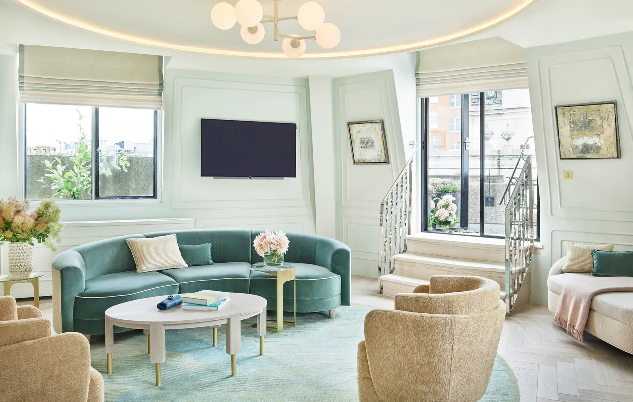 A suite living room with a green sofa and windows on two sides.