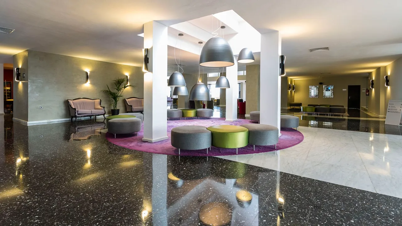Lobby at Palladium Hotel Don Carlos with grey and lime ottomans on a purple rug and dome pendants