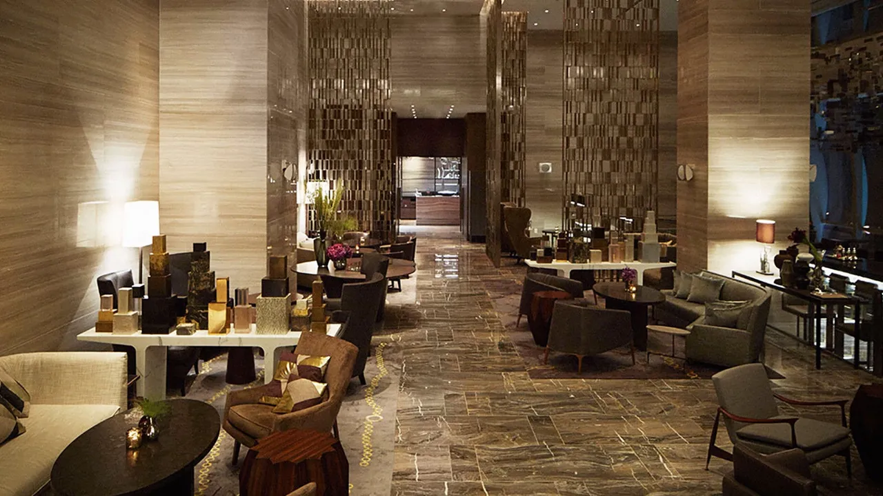 Lounge at Park Hyatt New York with marble floors, stone walls, armchairs and a display of gold objects