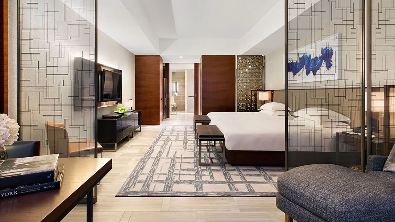 Suite at Park Hyatt New York with a large bed, geometric rug and grid-motif glass partitions