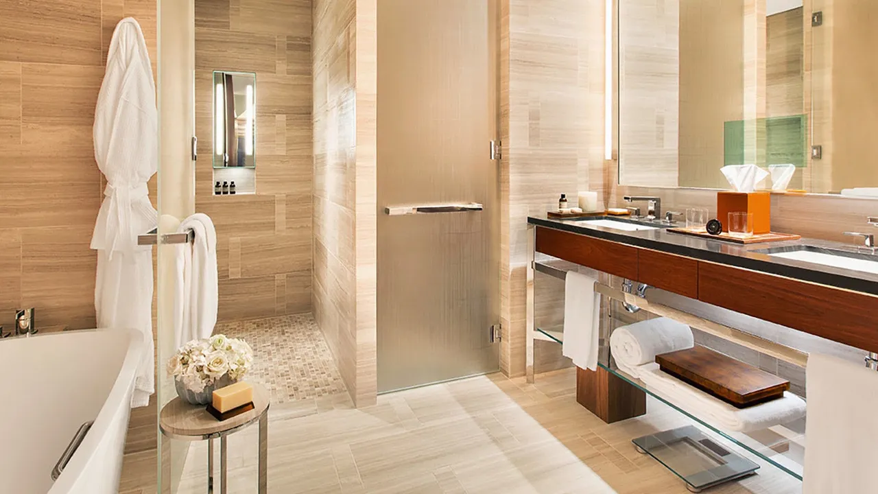 Bathroom at Park Hyatt New York with stone-clad walls, a soaking tub, walk-in shower and double vanity