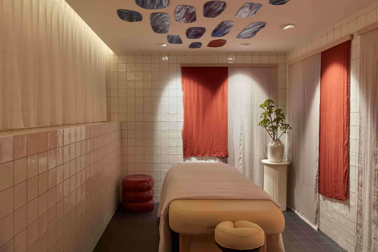 A treatment room in the beauty salon with a massage table and red curtains.