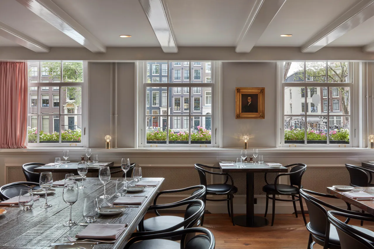 The Jansz dining room with set tables and windows onto the canal.