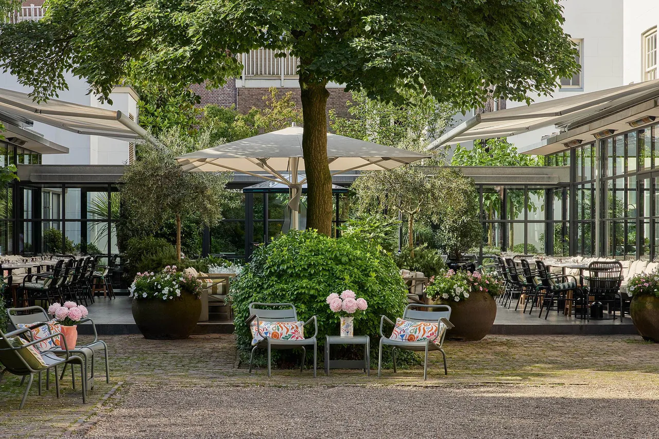 The leafy inner garden with tables under trees and parasols.