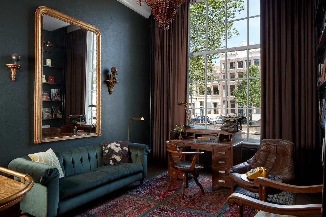 The Book Collector's Suite with a green sofa, dark walls and a canal view.