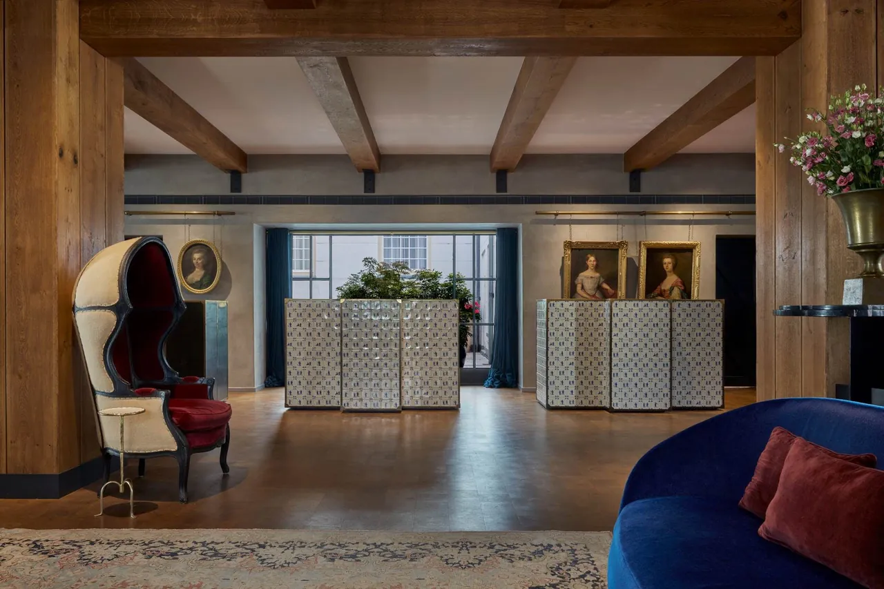 The lobby with wooden beams, a hooded armchair and a view through to the garden.