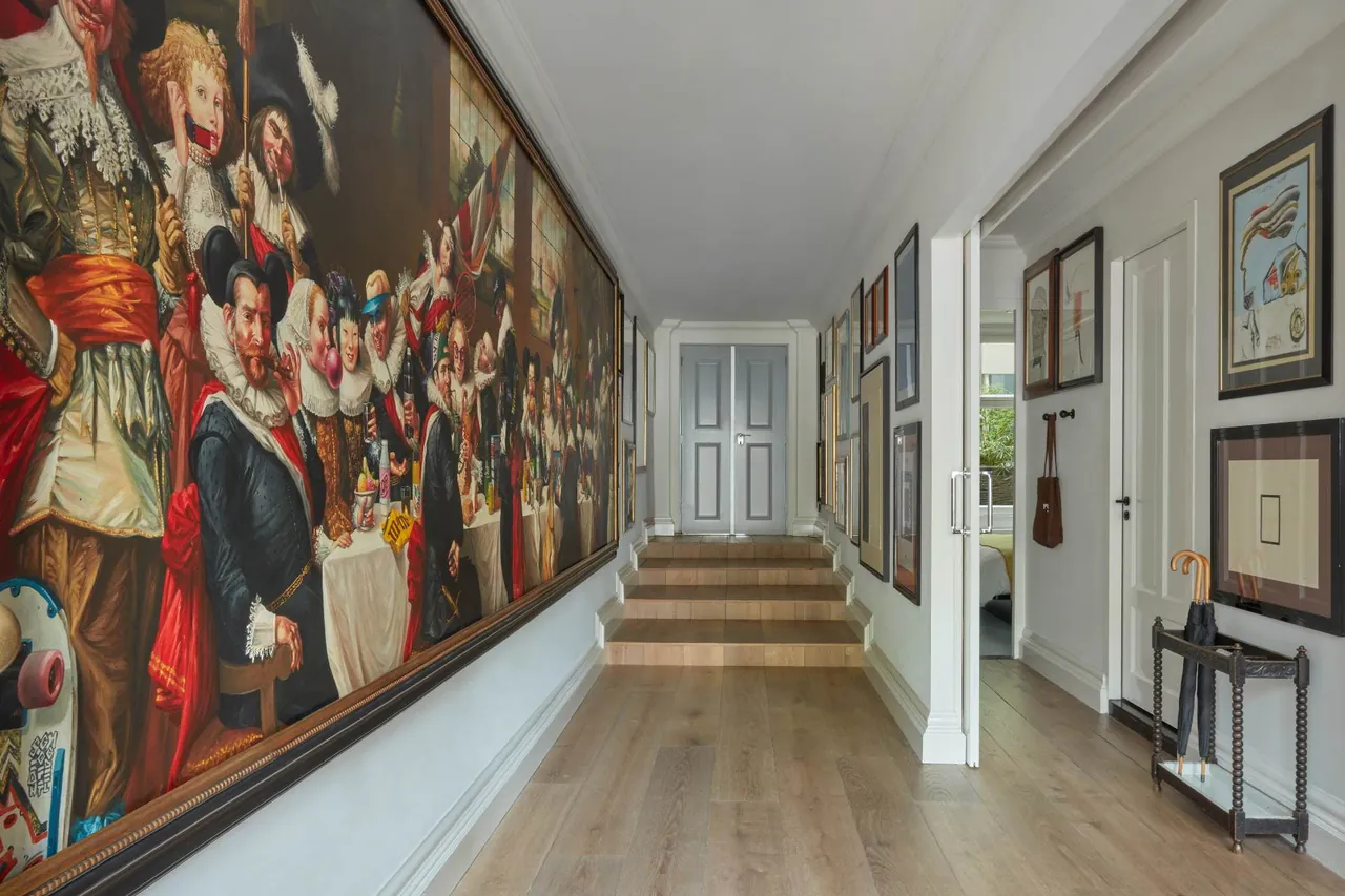 A long corridor lined with a large Golden Age style painting and framed artworks.