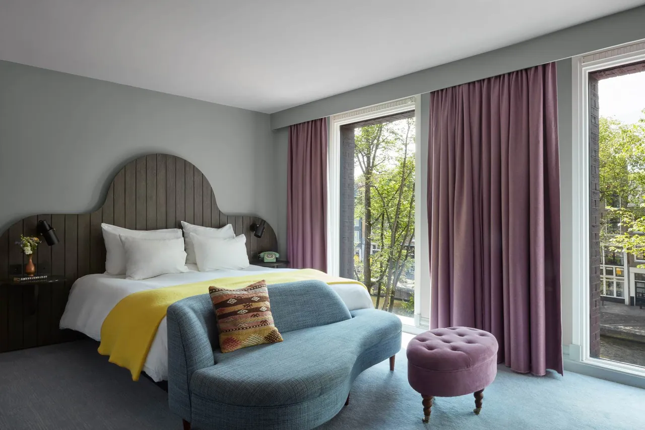 A classic king room with a curved headboard and tall windows over the canal.