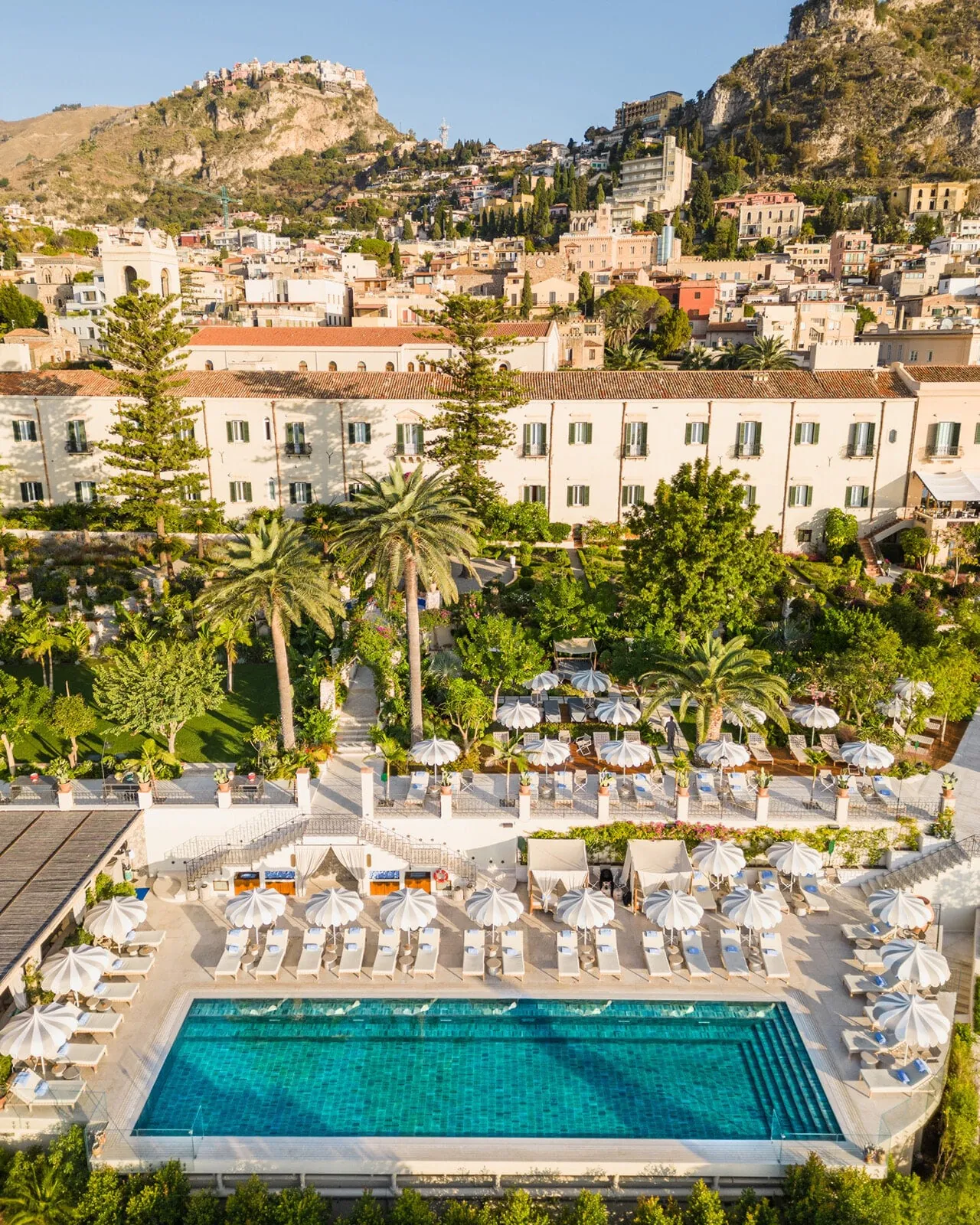 Aerial view of the pool and gardens, with the old town of Taormina climbing the hill behind.