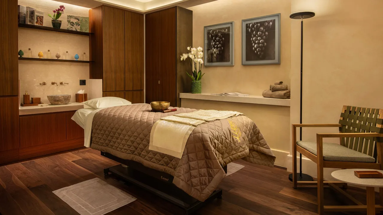 A spa treatment room with a massage bed in warm wood and soft light.