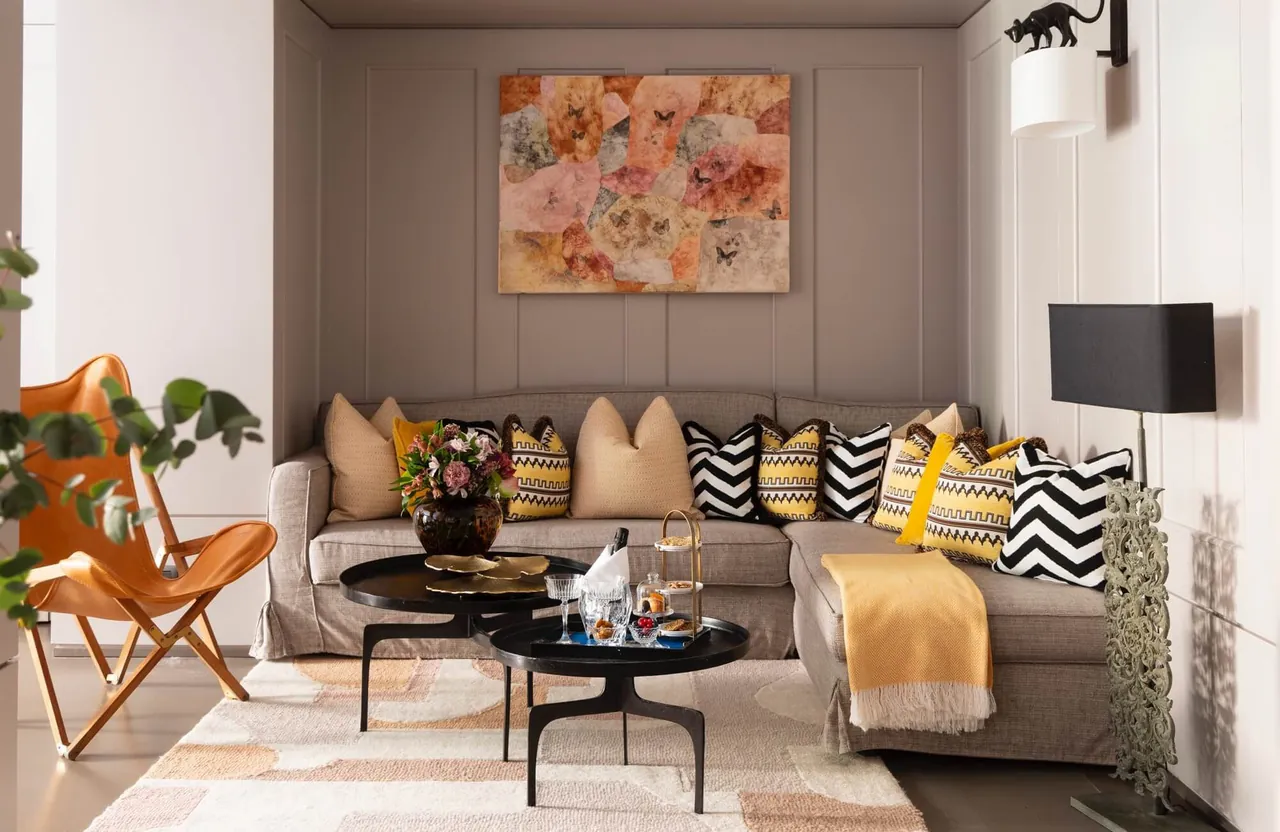 A junior suite living room with a long sofa, butterfly chair and floral artwork.