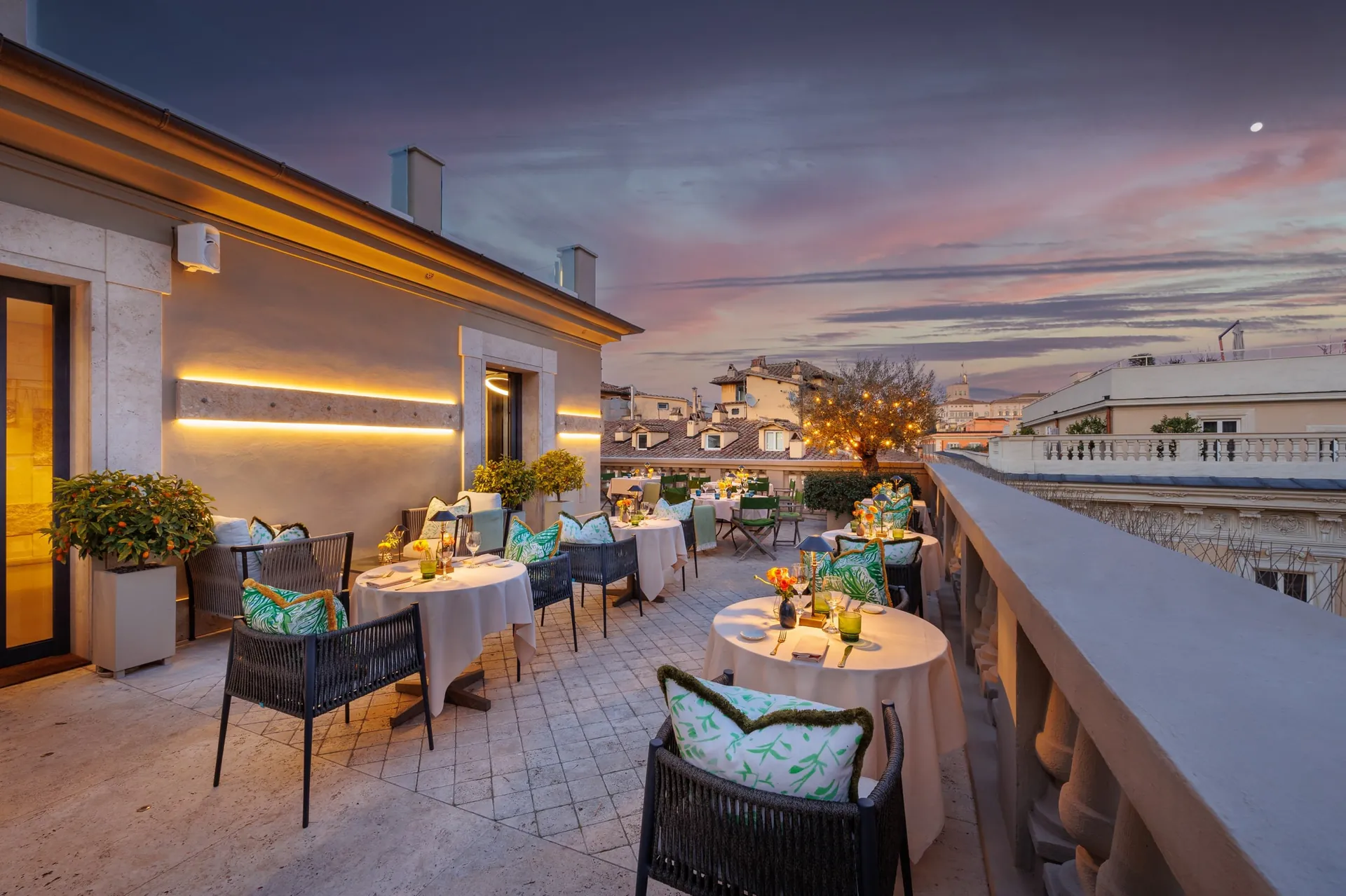 The rooftop terrace with lounge seating under a pink evening sky.