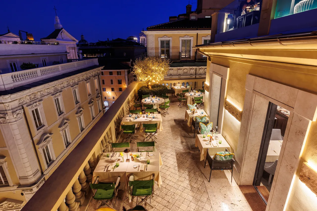The terrace restaurant glowing with warm lights at night between historic facades.