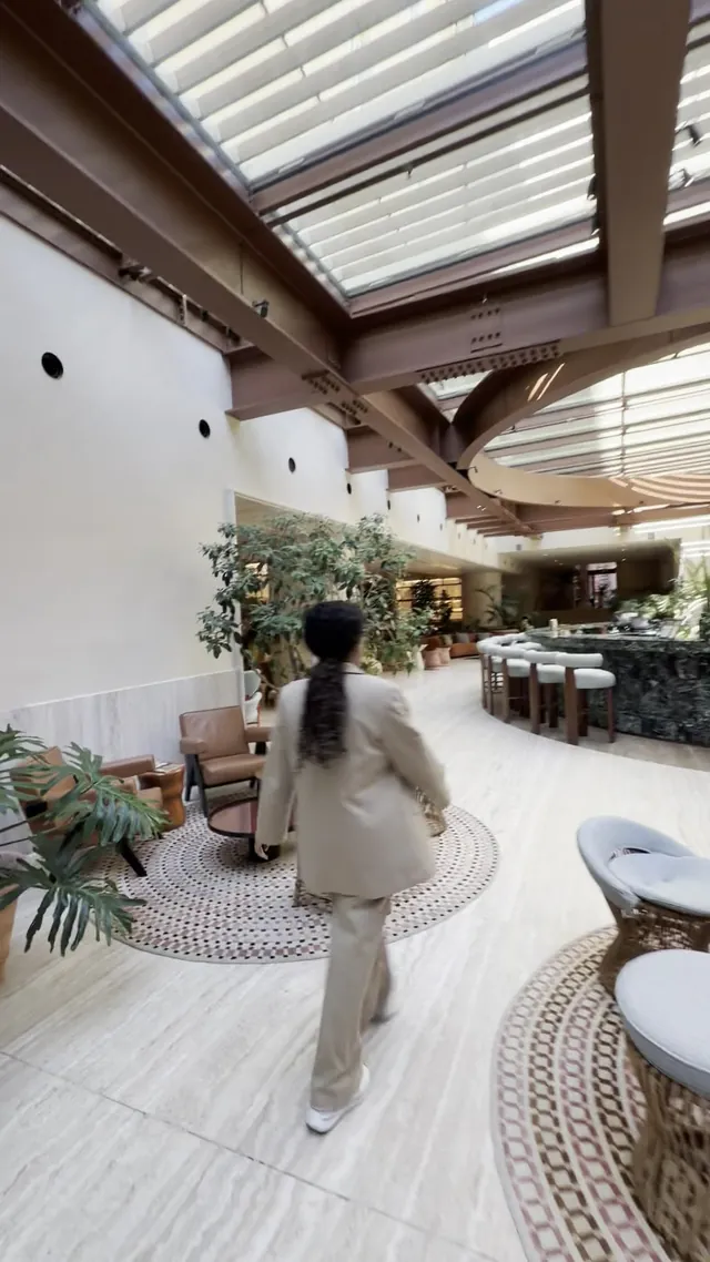 A guest walks through the leafy covered courtyard under timber beams.