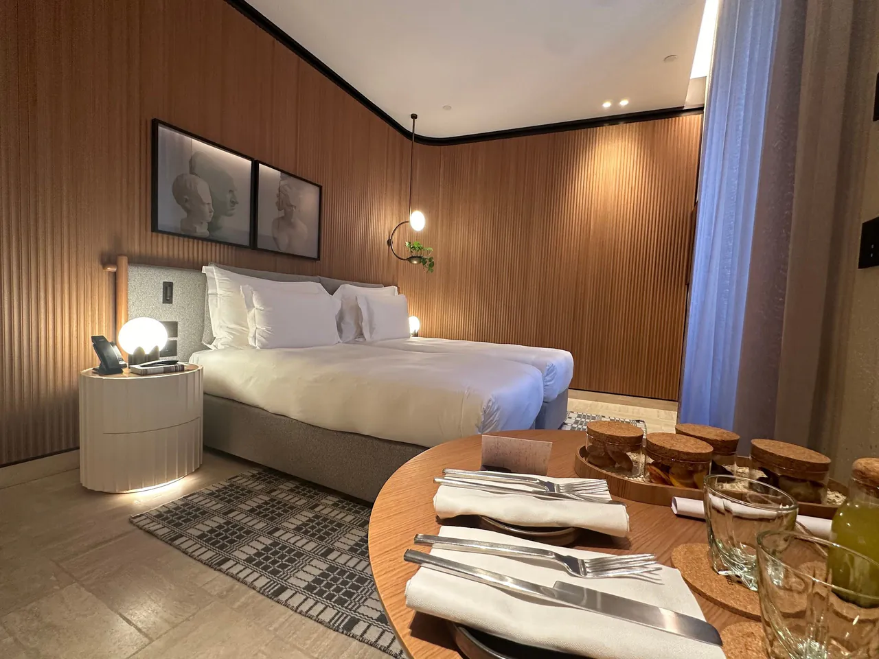 A guest room with oak panelling, a large bed and a table set for breakfast.