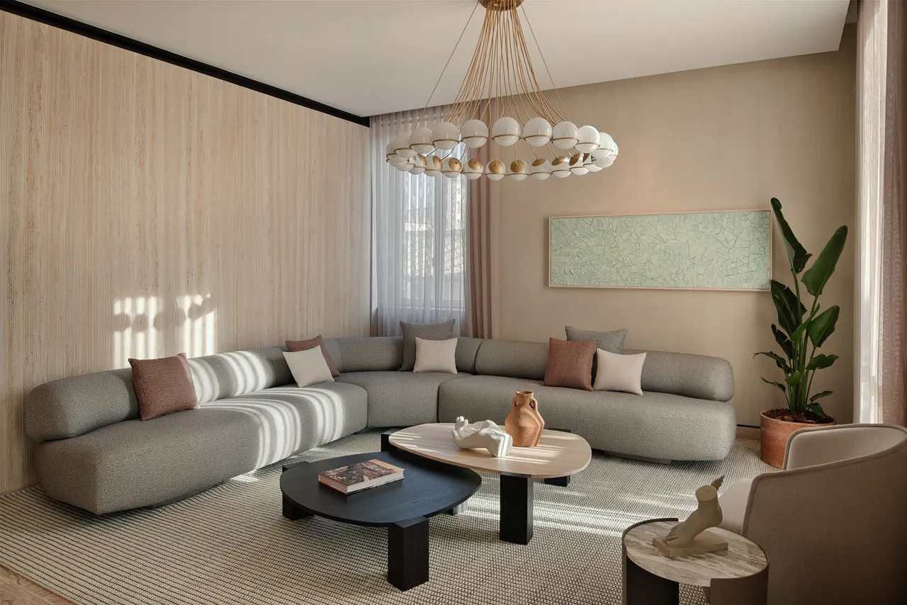A bright suite living room with a curved sofa and a sculptural chandelier.