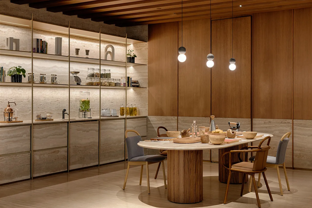 A wood-lined dining room with a round table and shelves of glassware.
