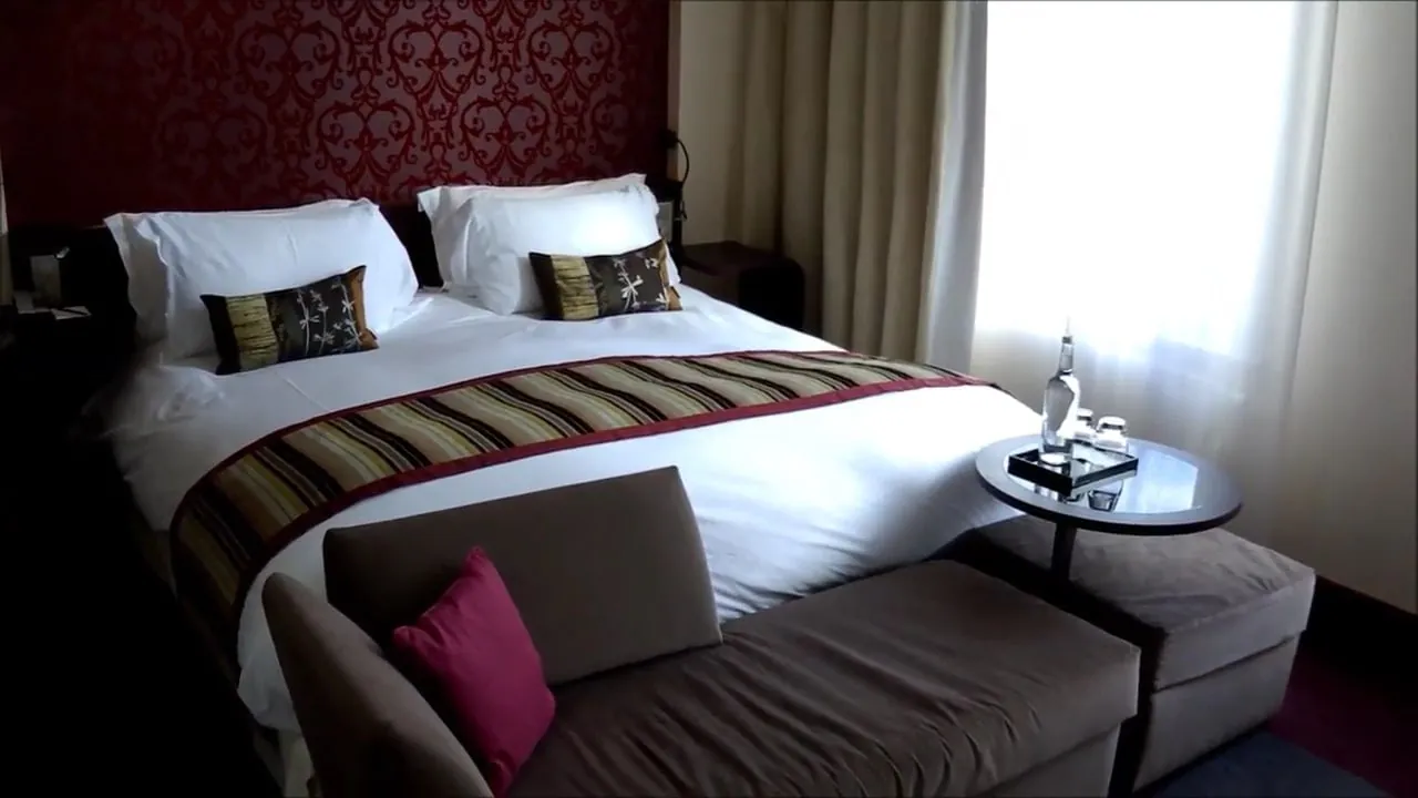A guest room with a large bed, a sofa and a bright window.