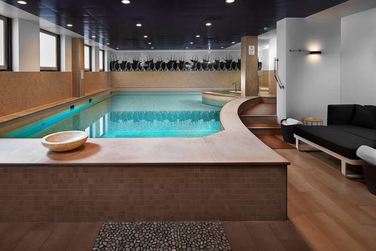 The indoor spa pool with loungers along a curved edge.