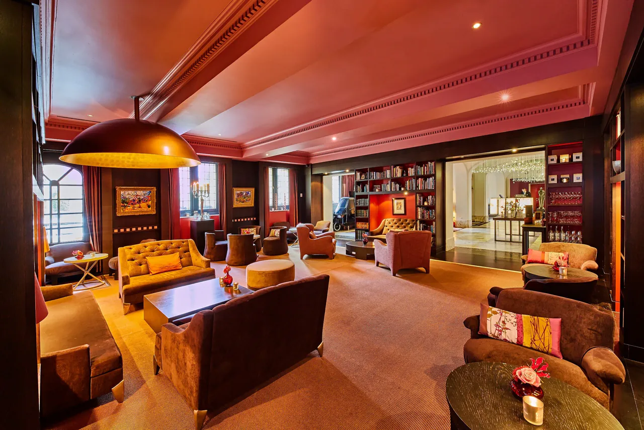 A warm lounge with colourful sofas and shelves full of books.