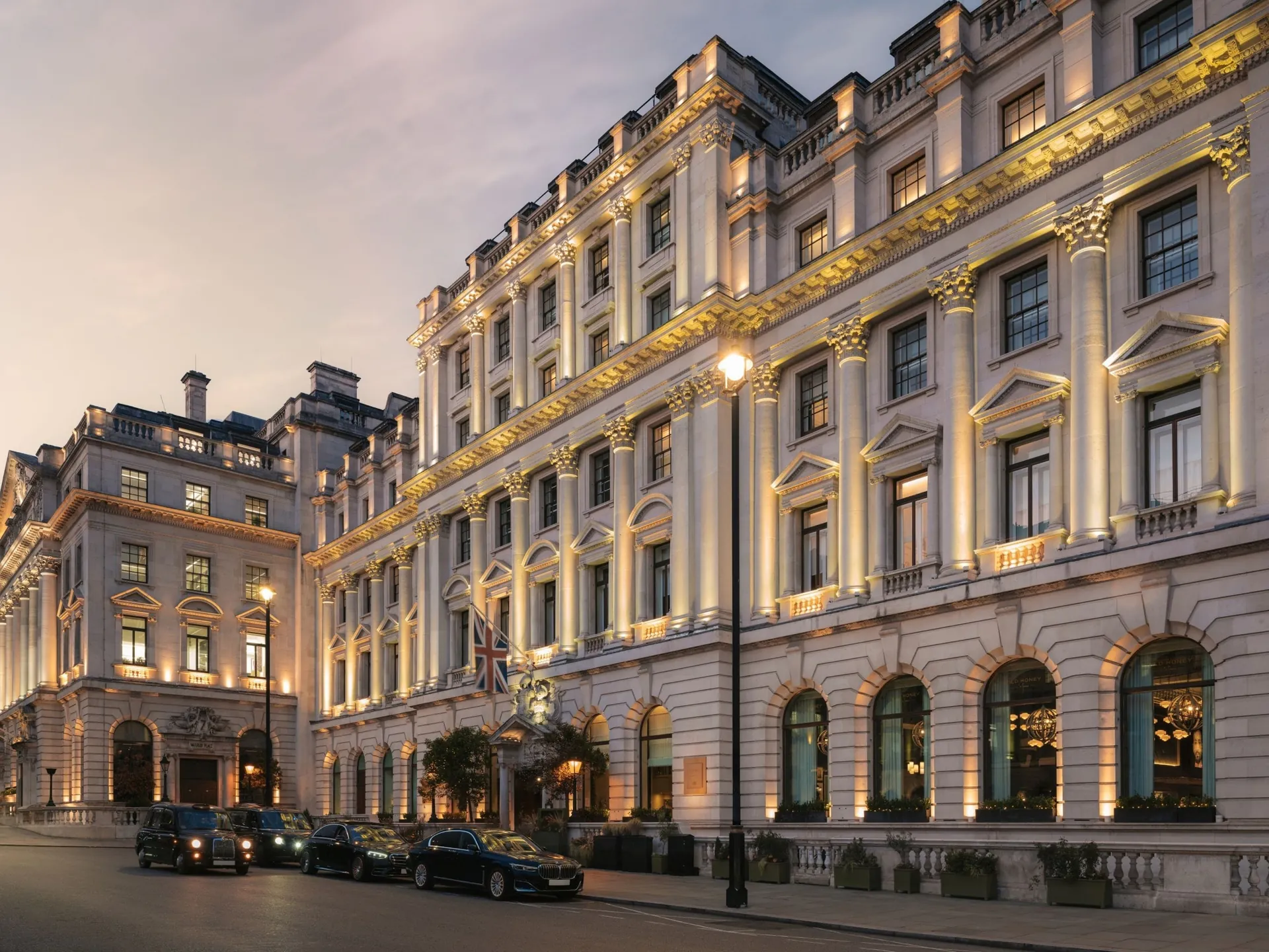 The neoclassical facade of the hotel on Waterloo Place lit up at dusk.